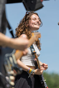 Evenementenfotografie; lachende zangeres met gitaar in de zon.